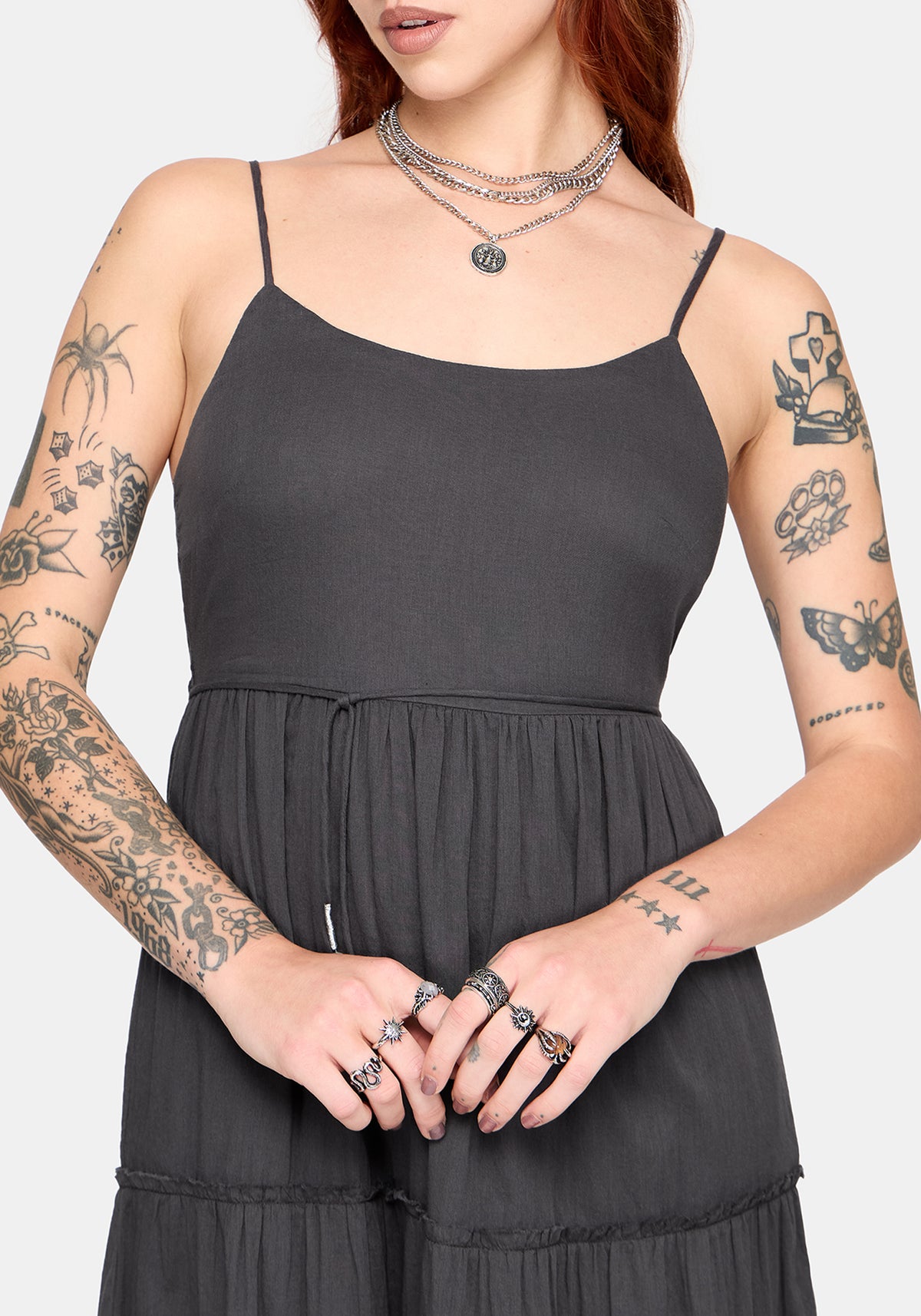 Model wearing a grey dress with tattoos on arms and neck against a white background