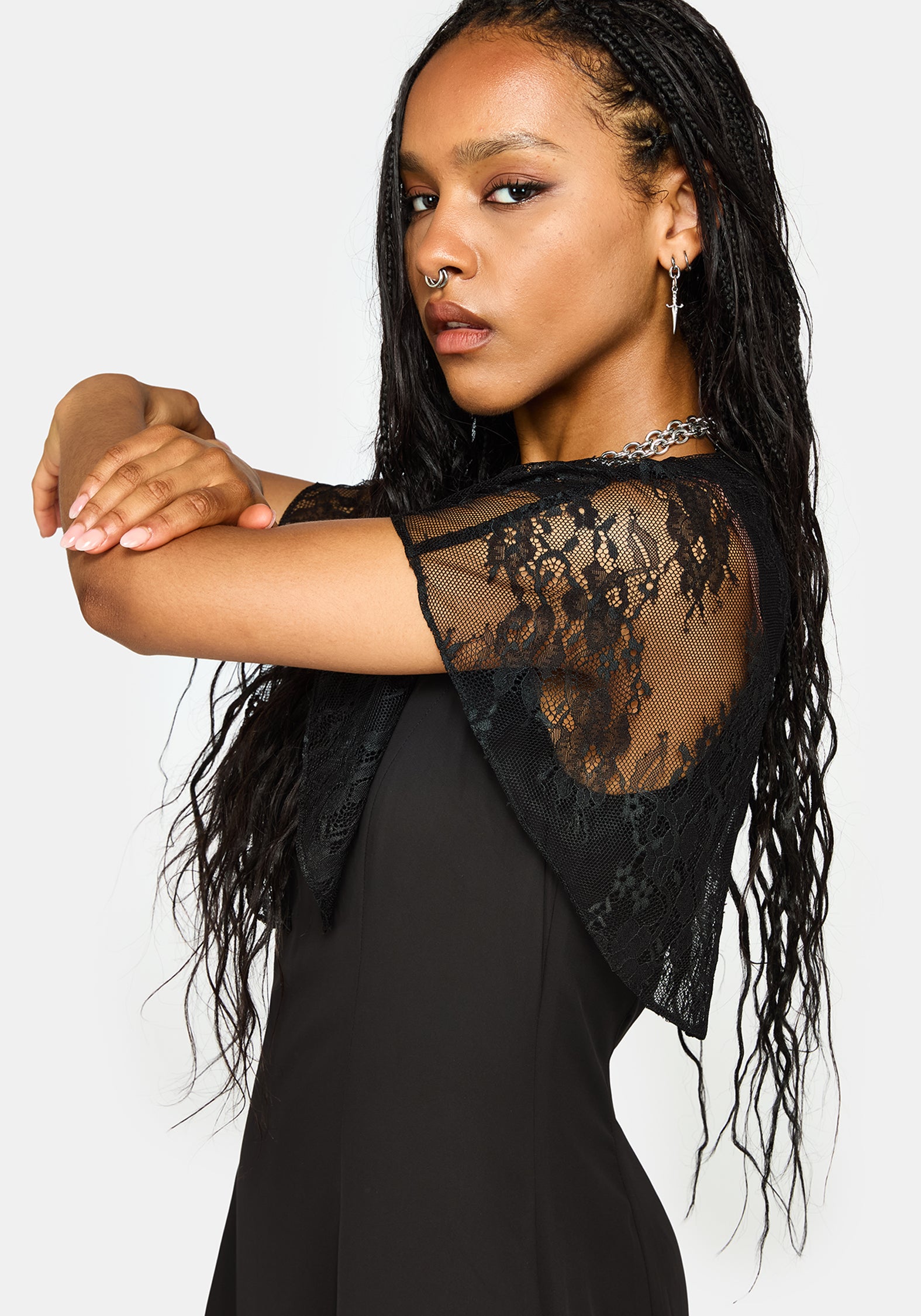 A woman modeling a black dress with sheer lace flutter sleeves against a light gray studio background.