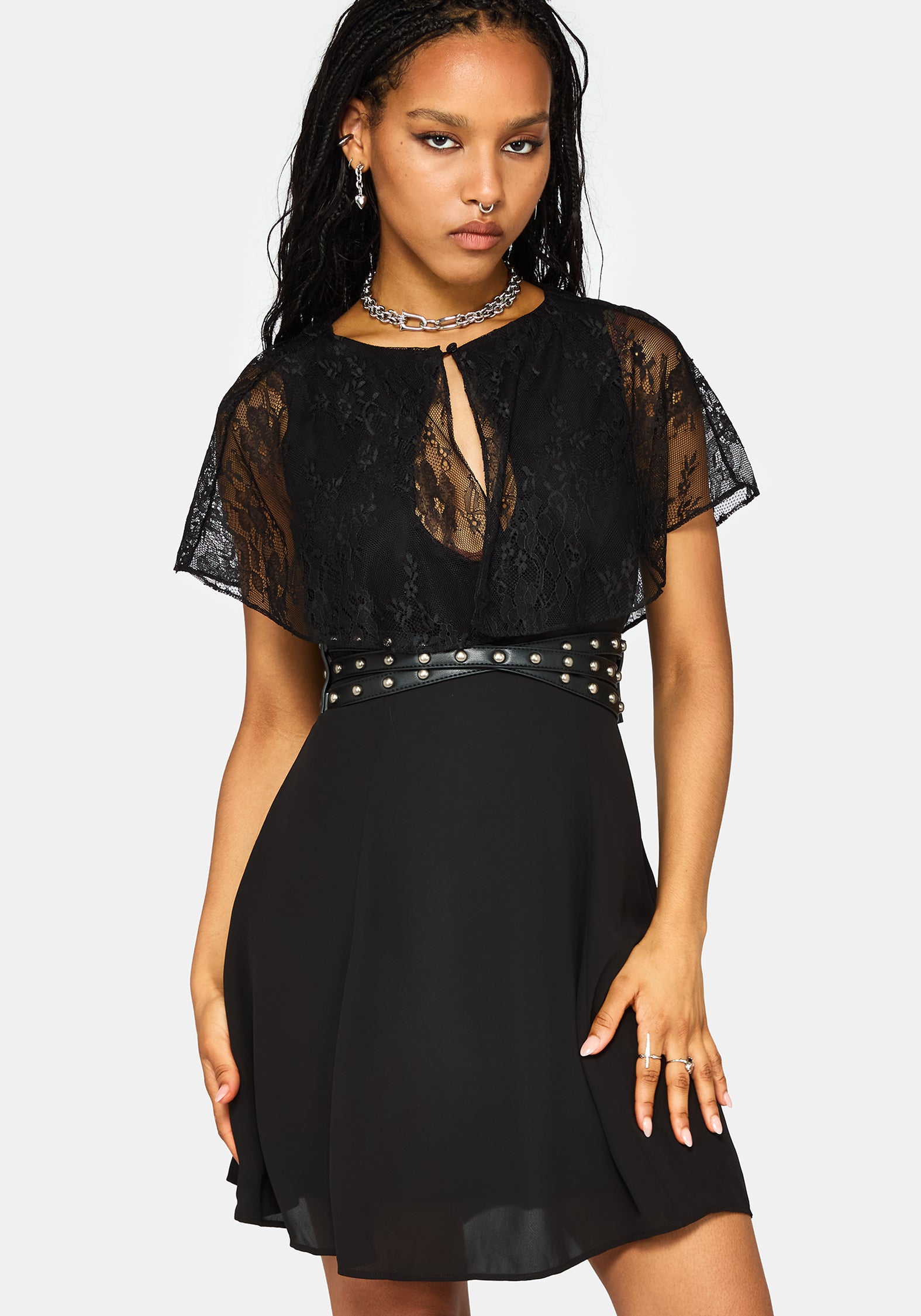 A woman modeling a black lace and chiffon mini dress with a studded waist belt, against a light gray background.