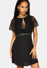 A woman modeling a black lace and chiffon mini dress with a studded waist belt, against a light gray background.