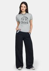 Woman wearing a gray t-shirt with a graphic design and black pants on a white background