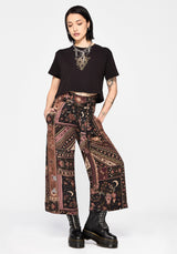 Person wearing a black crop top and patterned culottes on a white background