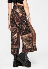 Person wearing patterned wide-leg culottes and black boots on a white background
