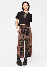 Person wearing a black top and patterned culottes on a white background